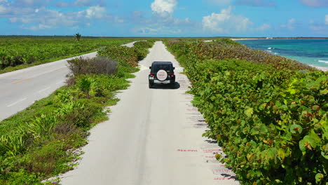 SUV-driving-on-tropical-coastline-road-on-sunny-summer-day-in-Cozumel-Mexico
