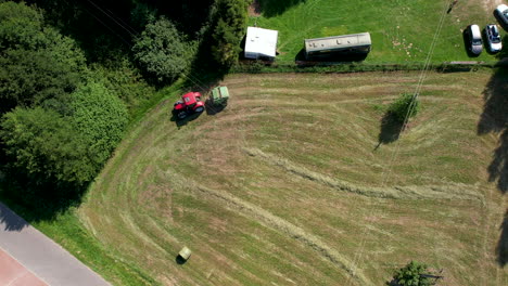 A-tractor-with-baler-at-work-on-a-freshly-mown-meadow---aerial-top-down