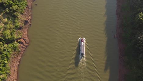 Eine-Dynamische-Luftaufnahme-Von-Oben-Nach-Unten,-Die-Seitlich-über-Dem-Touristenboot-Am-Fluss-Iguazu-In-Uruguay-Fliegt