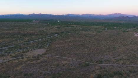 Drohnenaufnahme-Einer-Riesigen-Wüste-Mit-Sonnenuntergang-Hinter-Großen-Bergen-In-Der-Nähe-Von-Flagstaff-Arizona