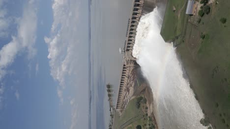 Formato-Vertical:-Presa-Hidroeléctrica-Que-Libera-Agua-De-Inundación-Forma-Un-Arco-Iris