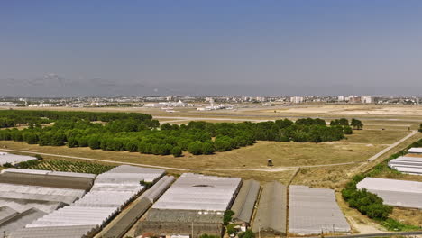 Antalya-Türkei-Antenne-V55-Niedrige-überführung-Yenigöl-Nachbarschaft-Aufnahme-Des-Gartenbaus-Mit-Gewächshausstrukturen,-Internationaler-Flughafen-Im-Hintergrund-–-Aufgenommen-Mit-Mavic-3-Cine-–-Juli-2022