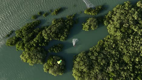 Kiteboarder-jumps-and-lands-in-clearing-amongst-Barra-Grande-Mangroves,-Brazil