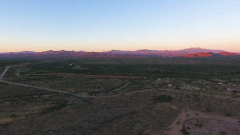 Panning-drone-shot-of-Arizona-Desert-with-mountains-glowing-pink-as-the-sun-sets-near-Flagstaff-Arizona