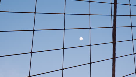 Majestic-Moon-in-dark-blue-dawn-sky,-view-through-cables-of-Brookly-bridge