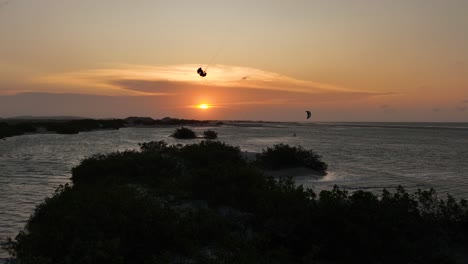 Kitesurfer-Machen-Einen-Großen-Sprung-über-Die-Sandbank---Silhouetten-Gegen-Den-Goldenen-Sonnenuntergangshimmel