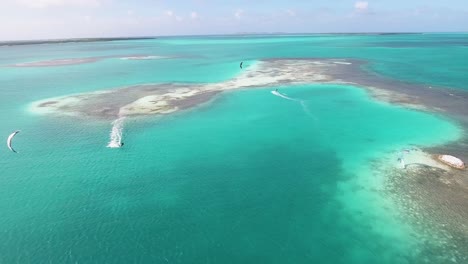Abenteuerlustiger-Mann-Kitesurfen-Wunderschöne-Karibische-Meeresfront-Kamera-In-Palafito,-Luftaufnahme-Los-Roques