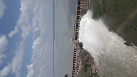 Vertical-format-aerial-orbit-of-hydro-dam-releasing-spring-flood-water