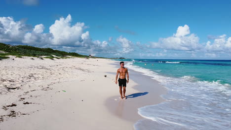 young-athletic-tan-man-walking-on-a-tropical-island-beach-in-Cozumel-Mexico-on-a-sunny-day