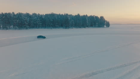 Car-drifting-fast-corners-on-snowy-Norbotten-woodland-ice-track-at-sunset,-aerial-view