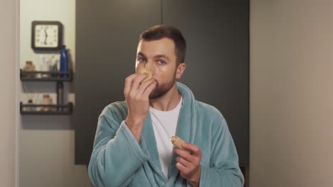 Portrait-of-a-handsome-well-groomed-man-applying-foundation-cream-on-his-face-with-a-sponge