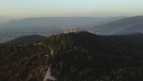 Aerial-view-over-telecommunication-towers-in-pine-forest-at-sunset