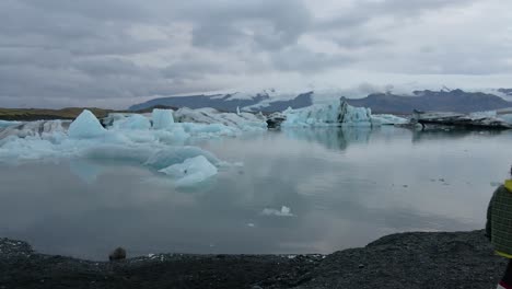 Isolated-and-unrecognizable-person-walking-along-banks-of-Jokulsarlon-glacier-lagoon,-Iceland