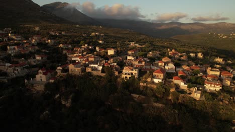 A-drone-flies-above-a-small-old-village-at-golden-hour-among-the-mountains-and-reveals-the-sea