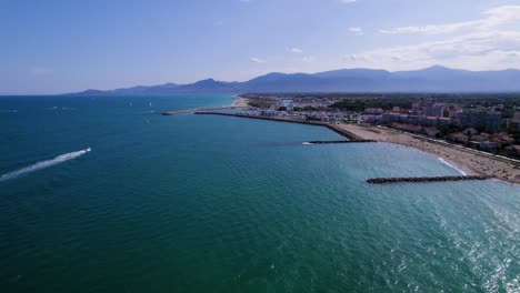 Aerial-panning-shot-showing-Beautiful-sandy-beach-and-blue-Mediterranean-Sea-in-France-during-summer---Mountain-range-in-background,-St-Cyprien