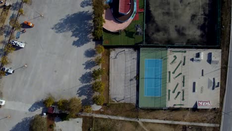 Luftschwenk-Von-Oben-Nach-Unten-über-Outdoor-Sportanlagen-Mit-Tennis,-Basketball,-Minigolf-Und-Skatepark