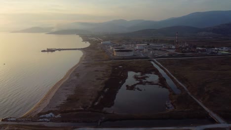 Aerial-pan-of-oil-refinery-factory-next-to-the-Aegean-sea-at-sunset