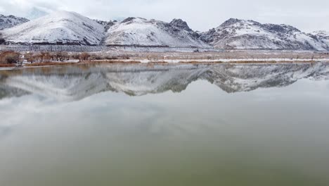 Diaz-lake-in-winter,-hills-covered-in-snow-with-beautiful-reflection-on-water