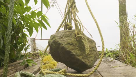 ,-A-Chinese--net-stone-used-for-fishing-in-backwaters-,A-stone-hanging-from-a-Chinese-net
