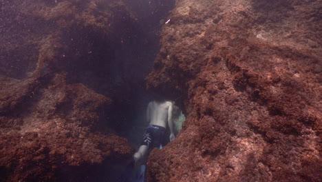 Ein-Junger-Mann-Schwimmt-Unter-Großen-Felsen-Des-Riffs