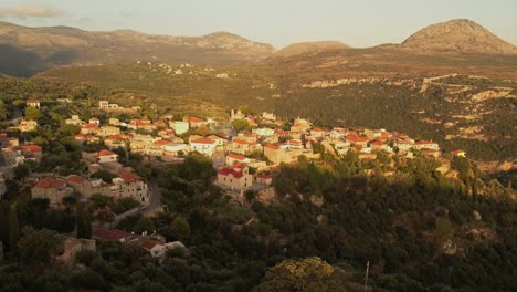 A-drone-flies-above-a-small-old-village-in-Greece-at-golden-hour-among-the-mountains-and-the-trees