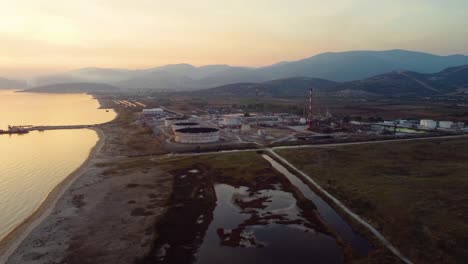 Aerial-pan-of-oil-refinery-in-a-big-valley-by-the-sea-at-sunset