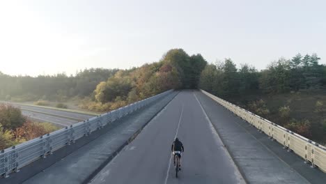 Behind-drone-shot-of-a-mountainbike-riding-on-an-overpass
