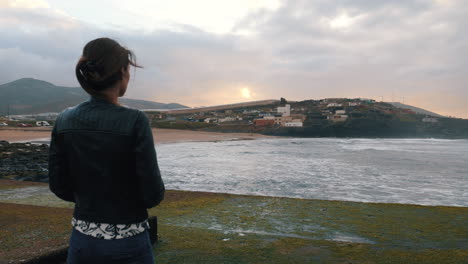 shot-of-a-woman-who-admires-the-sunset-on-the-beach-of-Boca-Barranco-in-the-city-of-Galdar,-on-the-island-of-Gran-Canaria