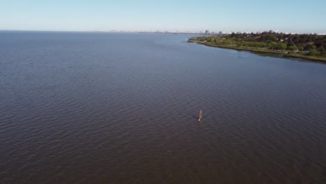 Aerial-view-of-person-practicing-wind-surfing-in-river-Near-shore-of-Vicente-Lopez-area-in-Buenos-Aires-during-sunny-day
