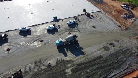 A-concrete-mixing-truck-drives-across-a-construction-site-with-a-drying-concrete-pad