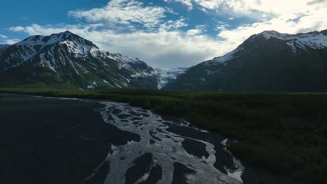Fliegen-über-Den-Geflochtenen-Fluss-Mit-Felsiger-Bergkette-Im-Hintergrund-In-Alaska,-Usa