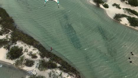Kiteboarder-Startet-über-Küstendüne-In-Lagune-Und-Macht-Kite-Loop