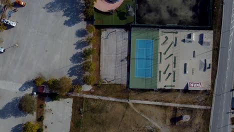 Aerial-top-down-pan-over-outdoor-sports-facilities-with-tennis,-basketball,-mini-golf-and-skate-park