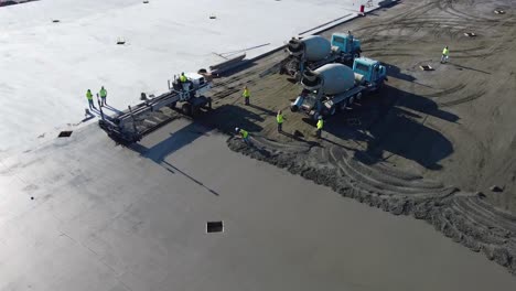 a-concrete-mixing-truck-uses-the-last-of-its-concrete-while-a-screed-smooths-out-the-concrete