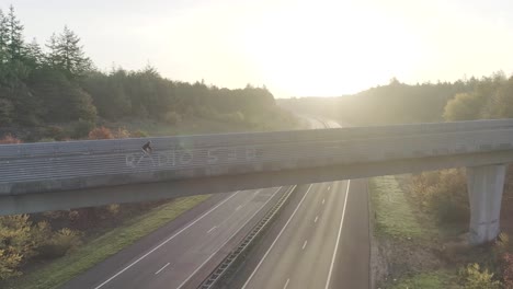 Drone-shot-at-sunset-or-sunrise-of-mountainbiker-riding-on-an-overpass