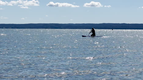 Silhouette-Of-Person-On-Surfboard-Paddling-In-The-Sea-In-Summer