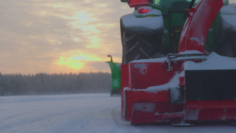 Tractor-snow-blower-clearing-Norbotten-Sweden-ice-track-snowdrift-at-sunrise,-Low-angle