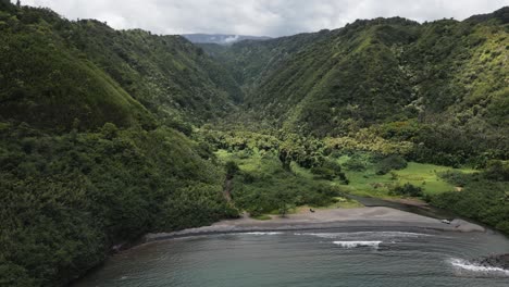 Aerial-of-rocky-beach-on-Maui-coast-in-Hawaii-with-green-mountain-valley