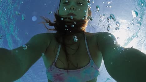 Underwater-selfie-of-beautiful-cute-little-red-haired-girl-holding-breath-while-floating-in-transparent-sea-water