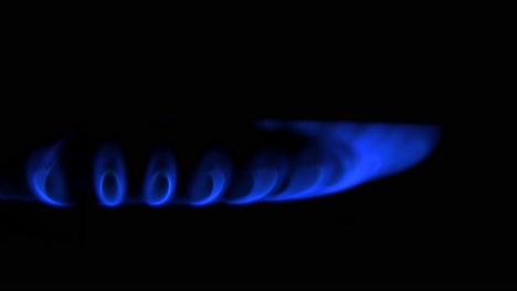 Gas-burning-from-a-kitchen-gas-stove,-dark-background,-cold-winter-and-energy-crisis-concept,-closeup-shot