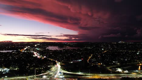 Thunderstorms-roll-through-the-North-West-of-Sydney,-Australia-in-the-distance-during-sunset-as-traffic-flows-through-the-nearby-roads-connecting-to-the-city
