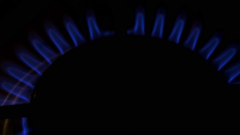 Gas-burning-from-a-kitchen-gas-stove,-dark-background,-cold-winter-and-energy-crisis-concept,-top-down-closeup-shot