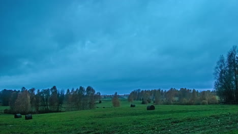 Dark-cloudscape-roll-above-green-vibrant-meadows,-fusion-time-lapse