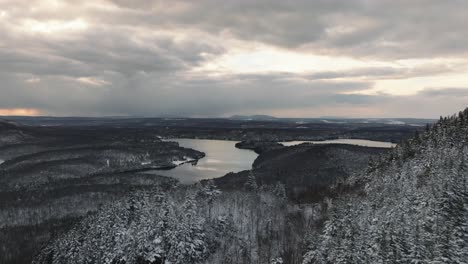 Lake-Stukely-Umgeben-Von-Verschneiten-Kiefernwäldern-An-Einem-Wolkigen-Wintersonnenuntergang-Im-Parc-National-Du-Mont-Orford-In-Quebec,-Kanada