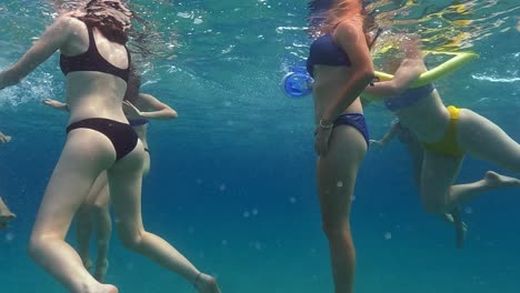 Under-water-surface-slow-motion-scene-of-group-of-girl-friends-swimming-in-crystal-clear-seawater