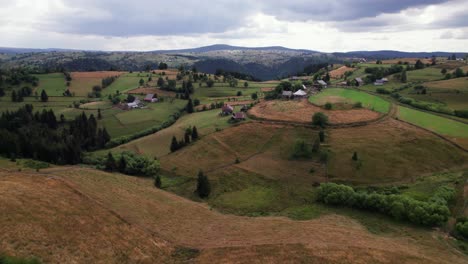 Aerial-of-agriculture-farmland-hill-with-houses-in-green-landscape,-Marisel