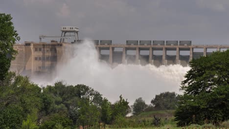 Downstream-view-of-power-dam-releasing-torrent-of-turbid-flood-water