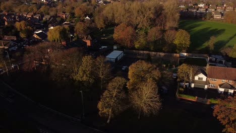 Idyllic-English-countryside-village-homes-surrounded-by-autumn-trees-at-golden-hour-aerial-view