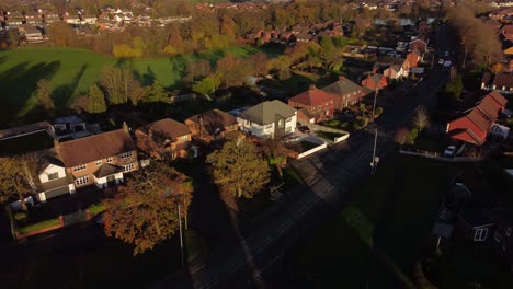 English-countryside-village-neighbourhood-homes-surrounded-by-Autumn-fall-trees-at-golden-hour-aerial-view