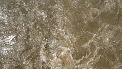 High-angle-view-of-muddy-brown-fast-flowing-river-water-rushing-past